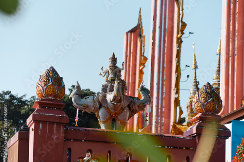 Foto Ornate temple sculpture on gateway with red columns and blue sky, featuring traditional Southeast Asian art