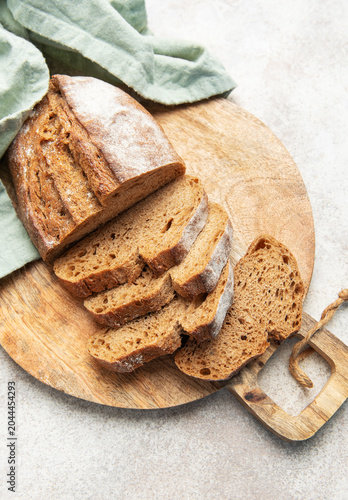 Canvas-taulu Slicing fresh whole grain rye bread on wooden board