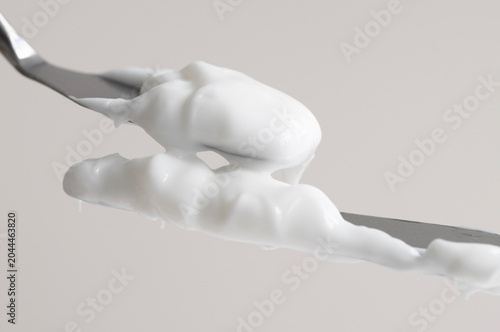 Two cosmetic spatulas with white texture of cosmetic hand cream on beige background, macro.