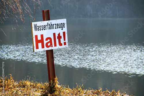 German sign Wasserfahrzeuge Halt, or Watercraft Stop, marking restricted vessel access on an inland waterway shoreline