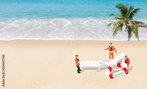 Miniature worker with beach chair and lifebuoy on tropical beach background, summer season concept