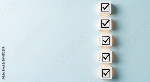 Minimalist checklist concept with five wooden blocks and check marks. Business task completion and survey results on blue background with copy space.