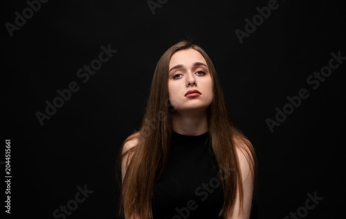 Fotografie Young woman with natural long hair expressing boredom and indifference against a