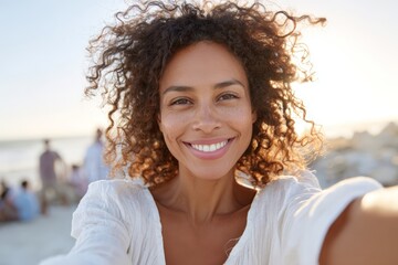 Sunlit beach selfie of a smiling woman with windblown hair for travel background and social media profile banner use