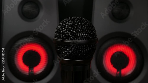 Microphone in Front of Studio Speakers with Red LED Light, Close-Up. The microphone rotates