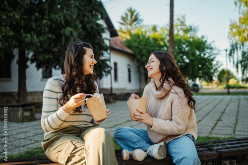 Women friends eating lunch outdoor in park