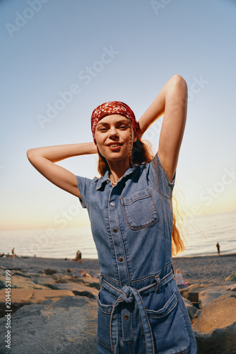 Φωτογραφία lifestyle woman in modern boho-western denim outfit posing on beach at sunset wi