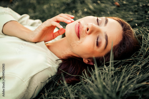 Young woman relaxing with eyes closed while lying in grass outdoors enjoying a peaceful natural moment