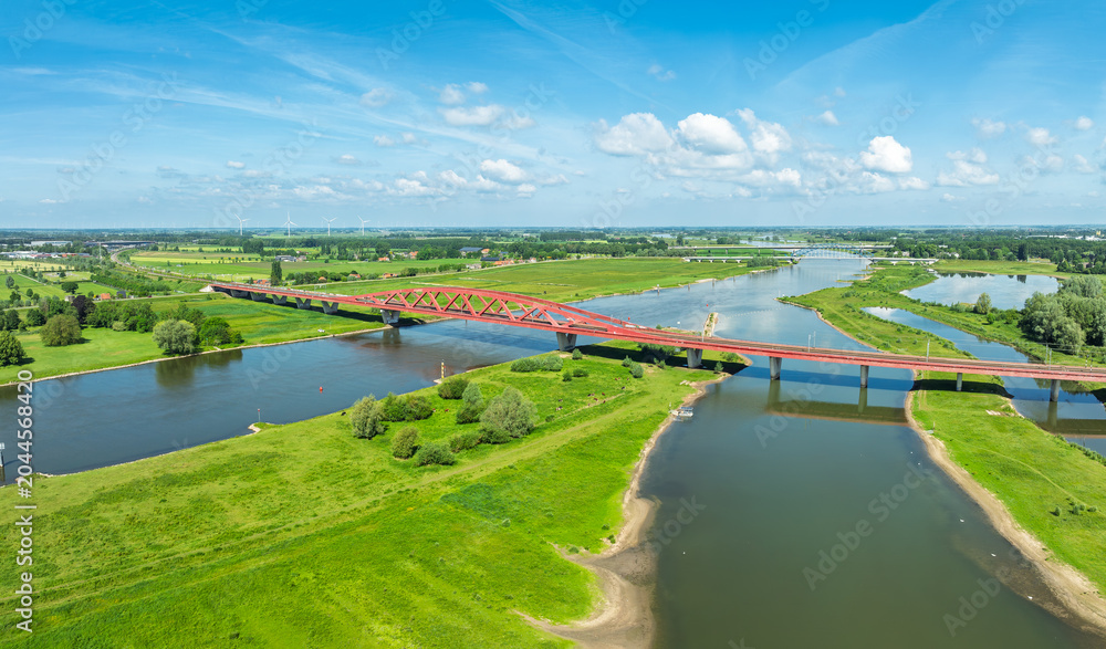 Obraz premium Aerial view of the Hanzeboog (Hanseatic Arch), a combined railway and cycle bridge spanning the IJssel river. The bridge was opened in June 2011