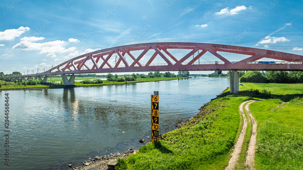 Fototapeta premium Aerial view of the Hanzeboog (Hanseatic Arch), a combined railway and cycle bridge spanning the IJssel river. The bridge was opened in June 2011