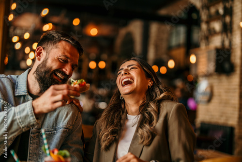 Tableau sur toile Happy couple enjoying a night out laughing and dining