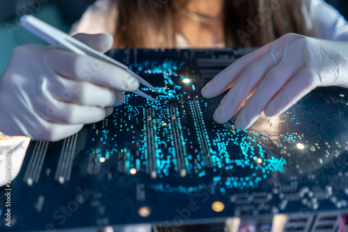 Foto A technician observes a circuit board while using a tool to inspect details in t