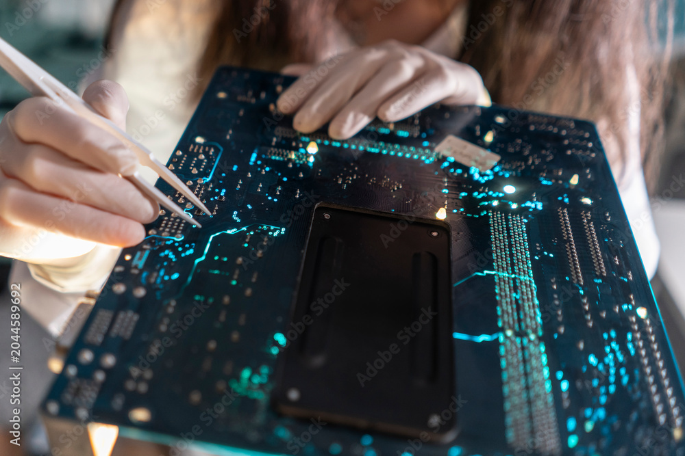 Obraz premium A technician uses tweezers to handle small components on a circuit board in a lab setting during the day