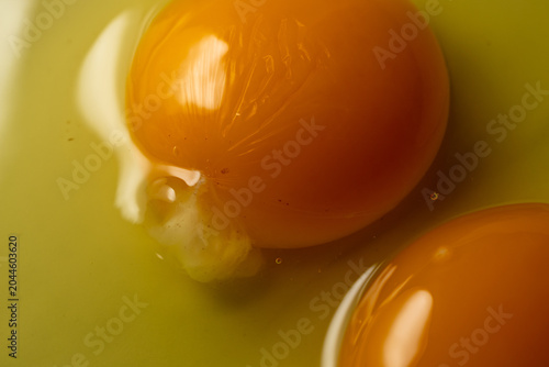 Macro close up of raw egg yolks with glossy texture and vibrant golden color. Fresh ingredient concept for baking, cooking and homemade food preparation.