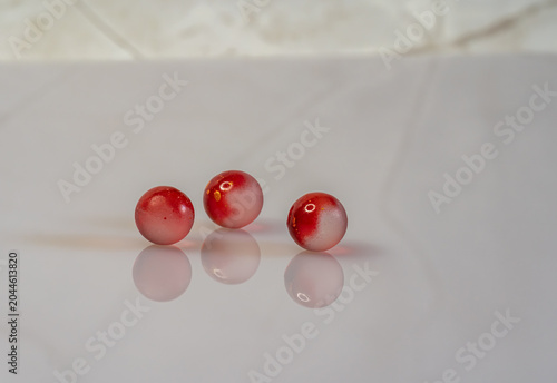 Bild auf Leinwand Red glass marbles with refections on white background