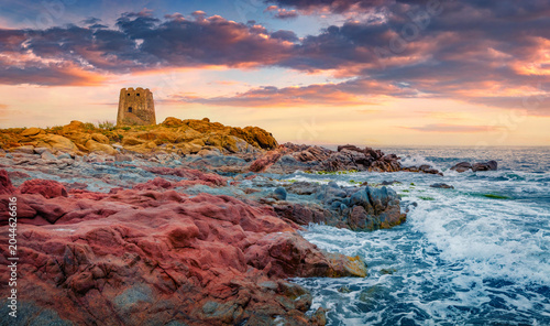Colorful summer sunset of rocky seashore with Torre di Bari tower. Picturesque morning scene of Sardinia island, Italy, Europe. Wonderful seascape of Mediterranean sea. 