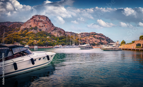 Attractive summer view of Poltu Quatu port with luxury yacht and motorboat. Amazing morning scene of Sardinia island, Italy, Europe. Picturesque Mediterranean seascape. Traveling concept background.