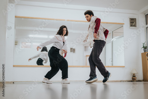 Фотография Two young dancers perform synchronized contemporary moves in a bright studio space