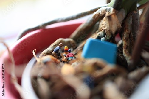 Miniature people on a roots of a flower.