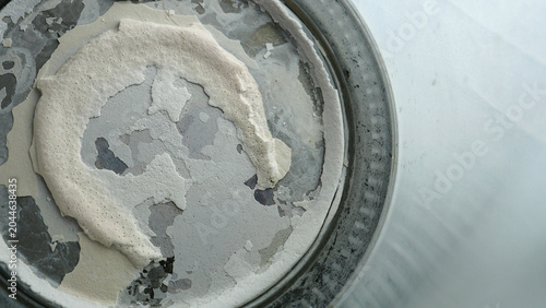 Close up of thick limescale and calcium deposits on the bottom of an old used kettle. Background texture of hard water scale buildup, mineral corrosion and damage inside electric boiler pot.