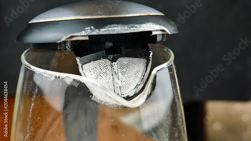 Close up of thick limescale and calcium deposits on the bottom of an old used kettle. Background texture of hard water scale buildup, mineral corrosion and damage inside electric boiler pot.