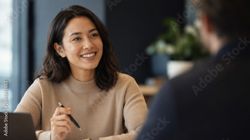 A professional woman with a smile on her face is engaged in a business meeting with colleagues in the office, engaging in diverse conversations and corporate communication.