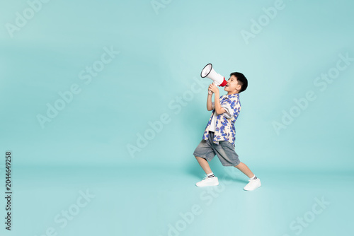 Konstfotografi Full body of a happy Asian boy shouting into a megaphone to announce news