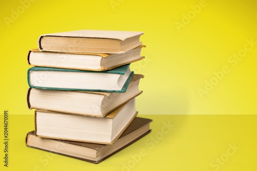 Stack of hardcover books on a yellow background with copy space for text