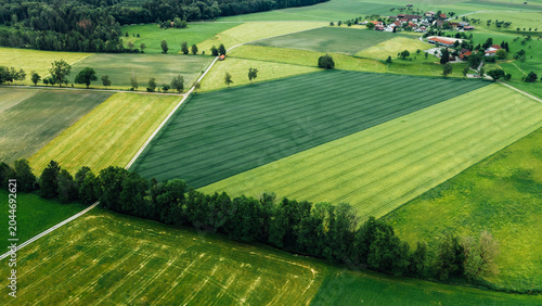 Aerial view of harvested field with farmhouse at edge