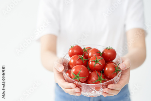 The young woman is holding tomato.
