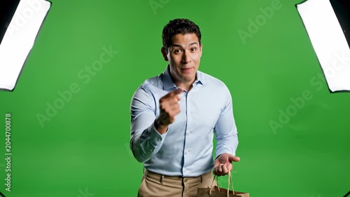 Male spokesperson holding shopping bag talking to camera green screen presenter