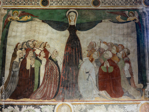 Schilderij op canvas A historic medieval wall fresco depicting the Virgin Mary spreading her protective cloak over kneeling believers, clergy, and figures of nobility, framed by decorative borders