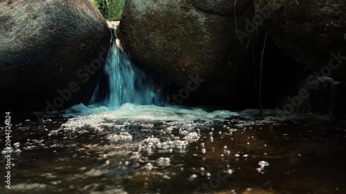 Small Waterfall Flowing Between Large Rocks in Rocky Stream