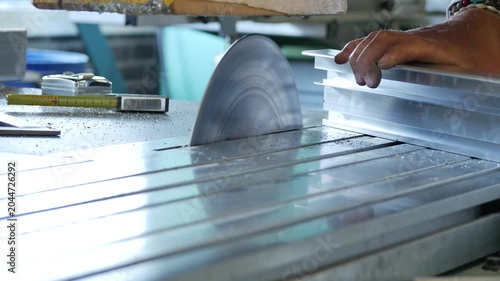 Worker Cutting Aluminum Profiles with Circular Saw in Metal Workshop