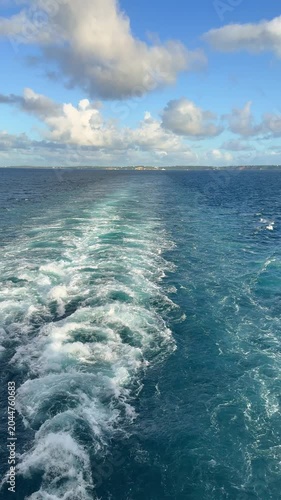 A Cruise ship wake on a beautiful sunny day with white clouds and blue seas on the Atlantic Ocean.
