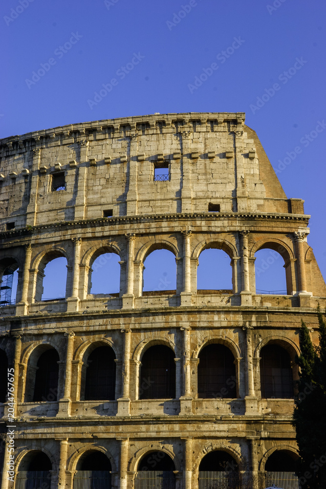 Obraz premium The Colosseum in Rome, Italy, under a clear blue sky.