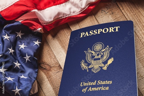 United States passport and American flag on a wooden table for travel and immigration concept