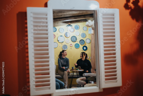 Photos Two friends sit at a small cafe table, talking and smiling while sharing drinks