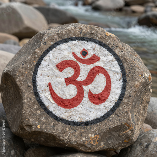 Sacred Om symbol painted on a rock by a river in Rishikesh
