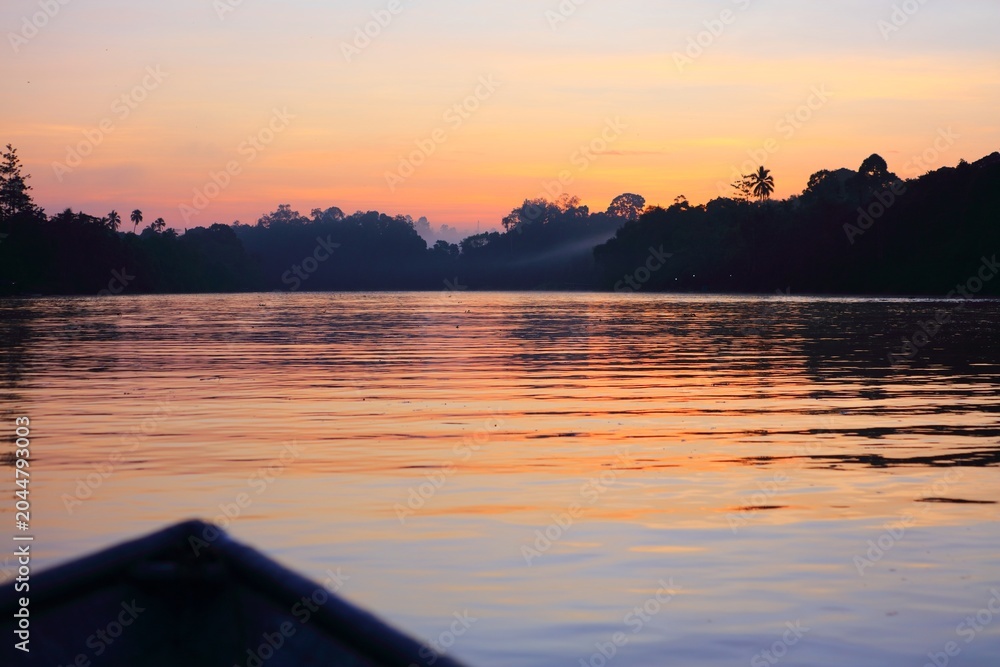 Obraz premium Sunrise and rainforest on Kinabatangan River in Sukau in Sandakan Division, in northeastern Sabah, Malaysia.
