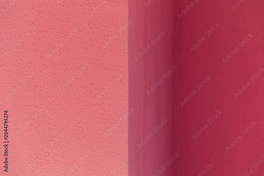 Fototapeta premium A textured wall surface painted in contrasting shades of dark and light pink divided by a vertical line, abstract background, minimalist design, vibrant color contrast.