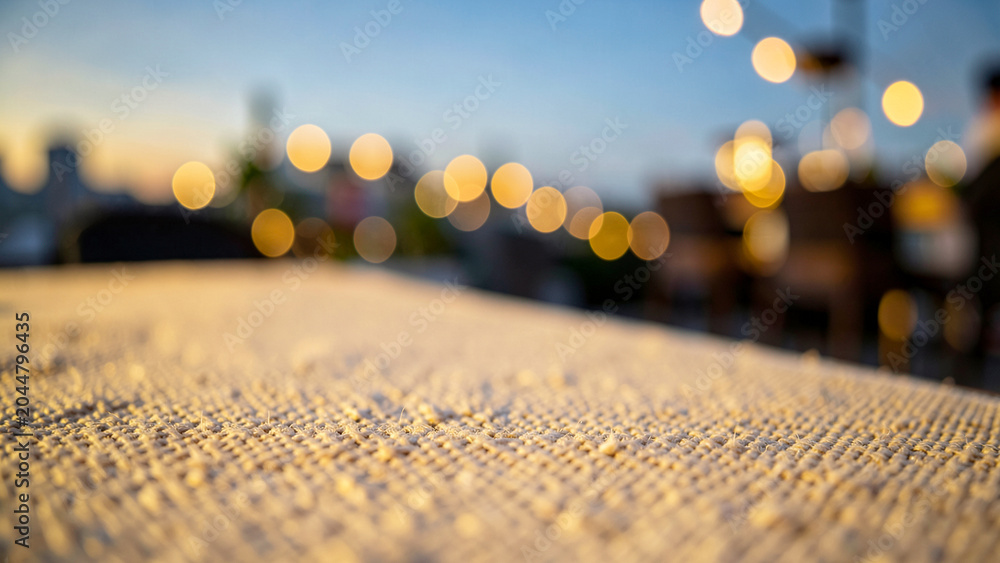 Fototapeta premium Granular woven textile surface under warm golden evening bokeh