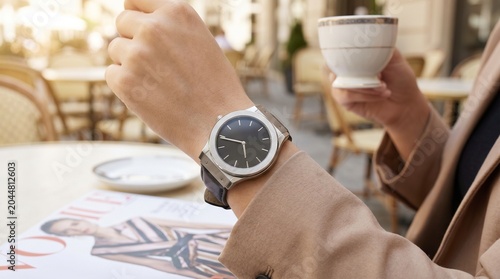 Woman wearing elegant wristwatch holding coffee cup at cafe with lifestyle