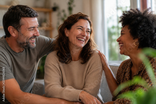 Three friends laugh together in a cozy, sunlit room