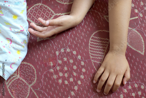 Photos Child forearms and hands resting on a patterned textile with a warm red backgrou