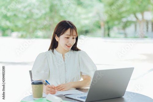 Photos テラスでパソコンを使う若い女性