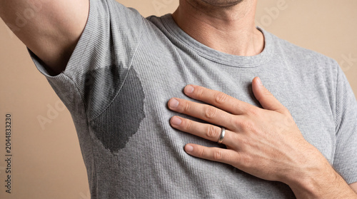 Man with hyperhidrosis sweating very badly under armpit in grey t-shirt