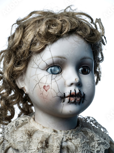 Close-up cinematic portrait of a possessed porcelain doll with cracked face and stitched mouth, head-and-shoulders composition, three-quarter pose with glassy mismatched eyes