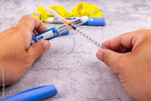Картината върху платно Hands holding a semaglutide glp1 medication injector pen and a hypodermic syringe for type 2 diabetes management and obesity care