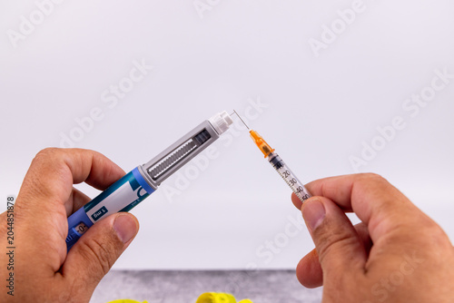 Tableau sur toile Close view of human hands holding a medical semaglutide glp1 injector pen and a hypodermic syringe for chronic diabetes therapies